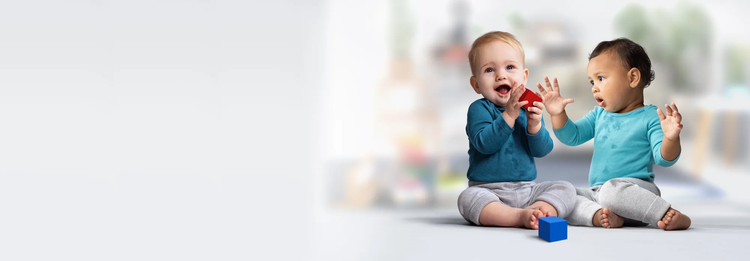 Two infants engaging in block play on the floor.