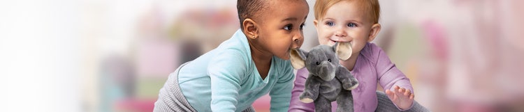Two infants holding a toy elephant by its ears in their mouths.