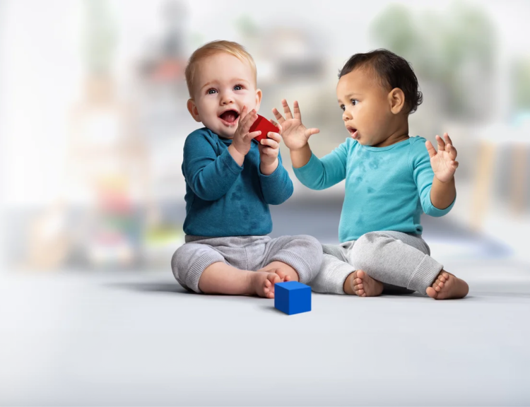 Two infants engaging in block play on the floor.