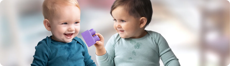 A young child showing a toddler a purple ball