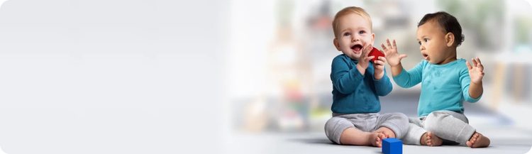 Two infants engaging in block play on the floor.