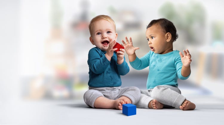 Two infants engaging in block play on the floor.