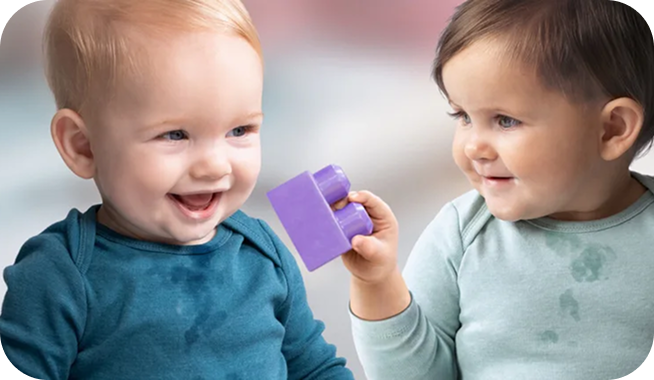 A young child showing a toddler a purple ball
