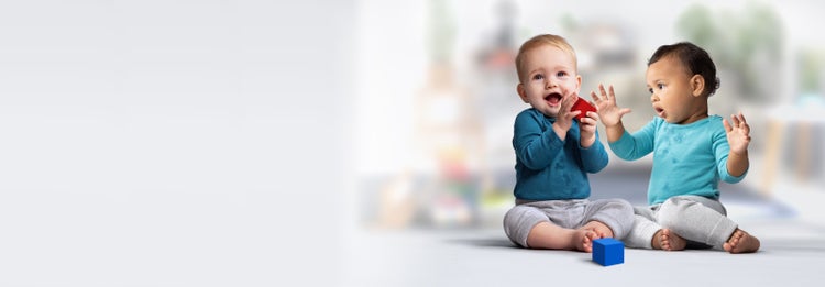 Two infants engaging in block play on the floor.