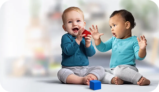 Two infants engaging in block play on the floor.