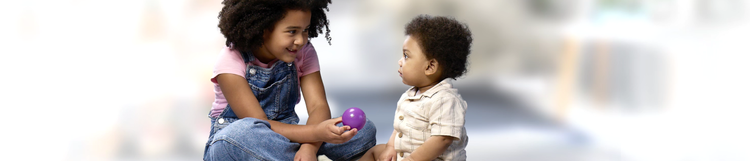 A young child showing a toddler a purple ball